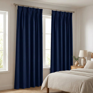 Rideau occultant bleu marine suspendu à une tringle devant une fenêtre dans une chambre lumineuse