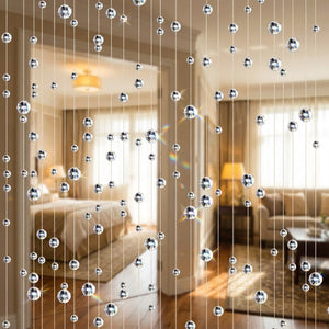 Rideau de perles de cristal transparent suspendu dans l'encadrement d'une porte lumineuse