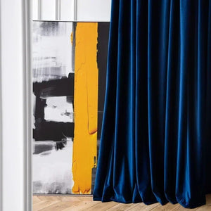 Rideau en velours bleu roi tombant devant un tableau abstrait noir et jaune
