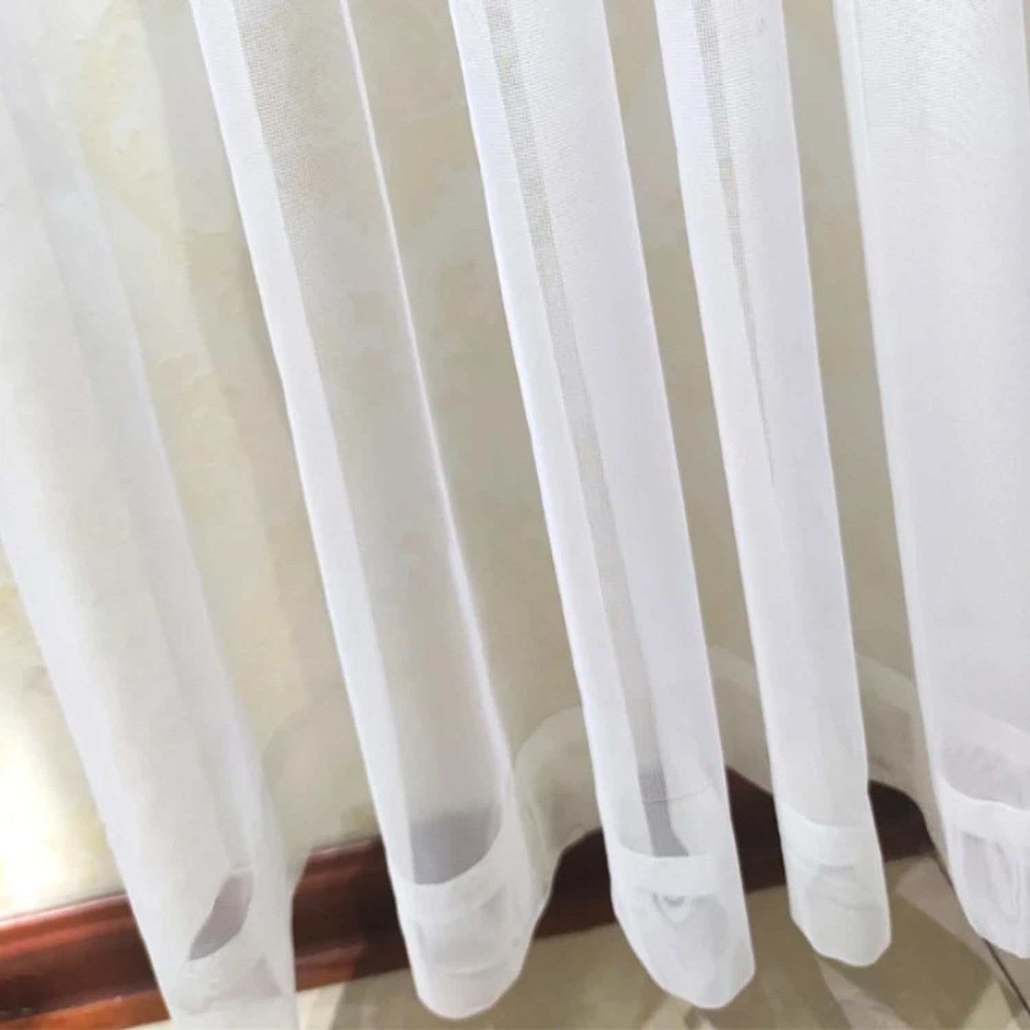 Détail de l'ourlet du bas du rideau voilage en tulle blanc