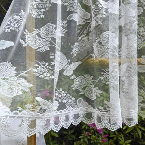 Détail du tissage en dentelle du rideau voilage montrant le motif fleurs et papillons