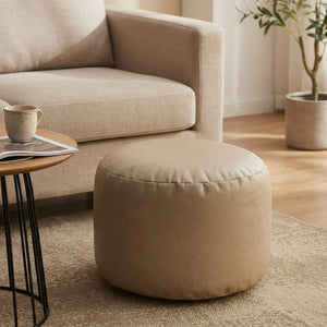 Pouf ottoman rond en simili cuir beige rembourré dans un salon chaleureux