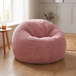 Pouf rose en velours côtelé posé au sol dans un salon clair