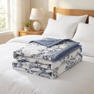 Couvre-lit matelassé d'été réversible à roses bleues plié sur un lit dans une chambre lumineuse