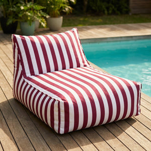 Pouf géant flottant à rayures rouge posé au bord d'une piscine