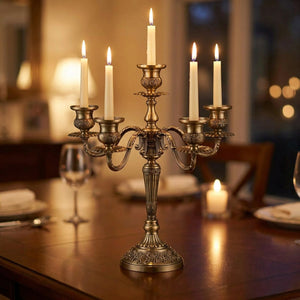 Chandelier en métal bronze à cinq branches style ancien posé sur une table sombre avec bougies