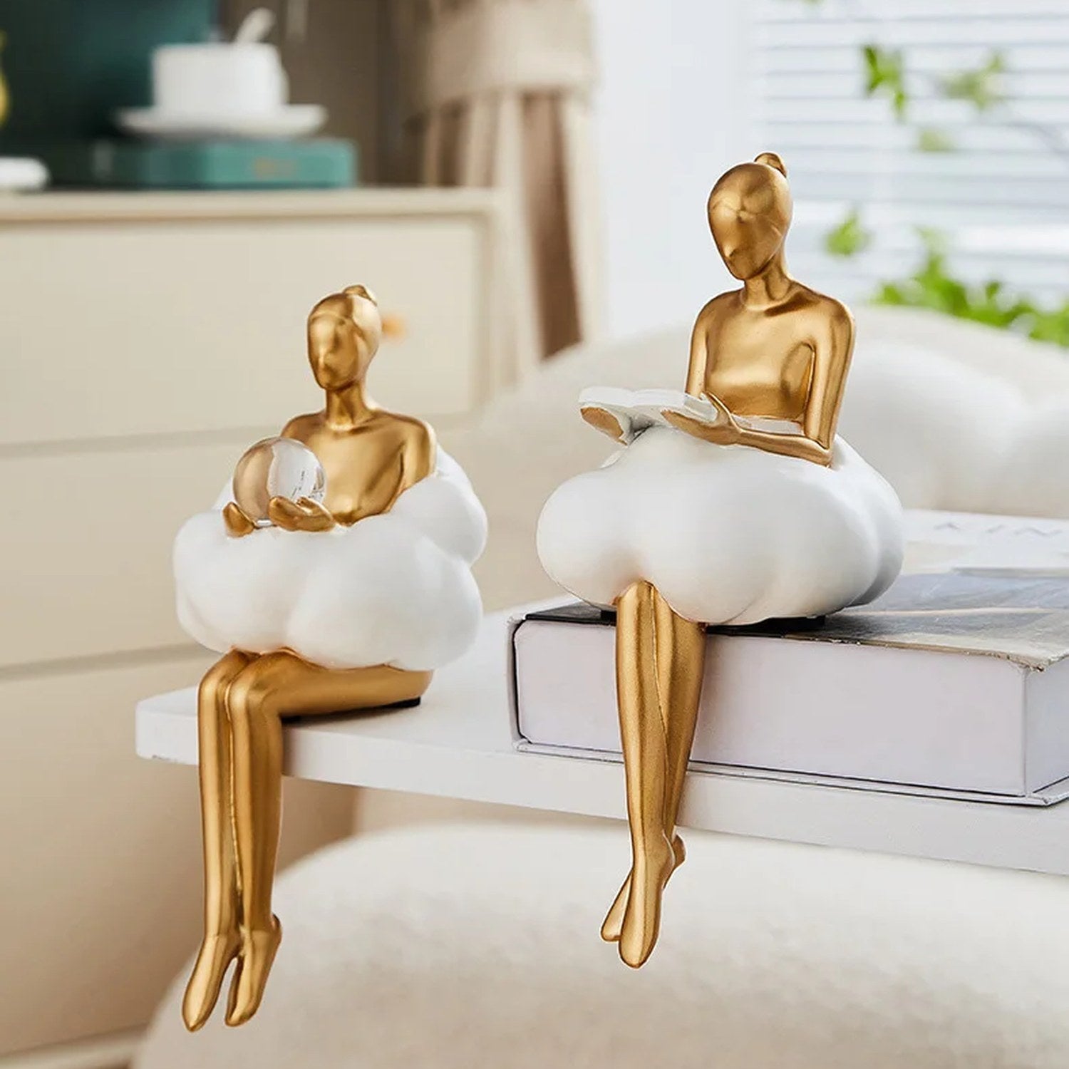 Deux sculptures femme dorée sur étagère blanche dans décor intérieur lumineux