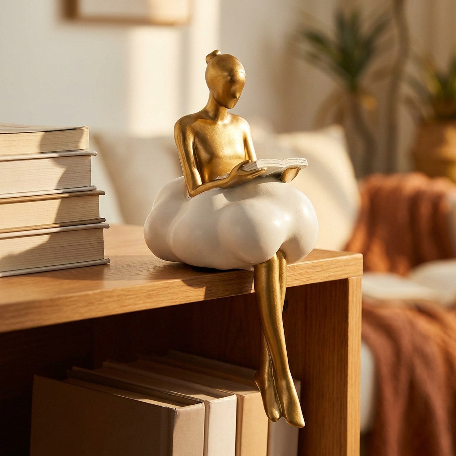 Figurine lectrice en résine dorée avec livre ouvert sur étagère en bois