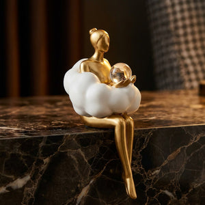Figurine pensive en résine dorée avec boule de cristal sur surface sombre