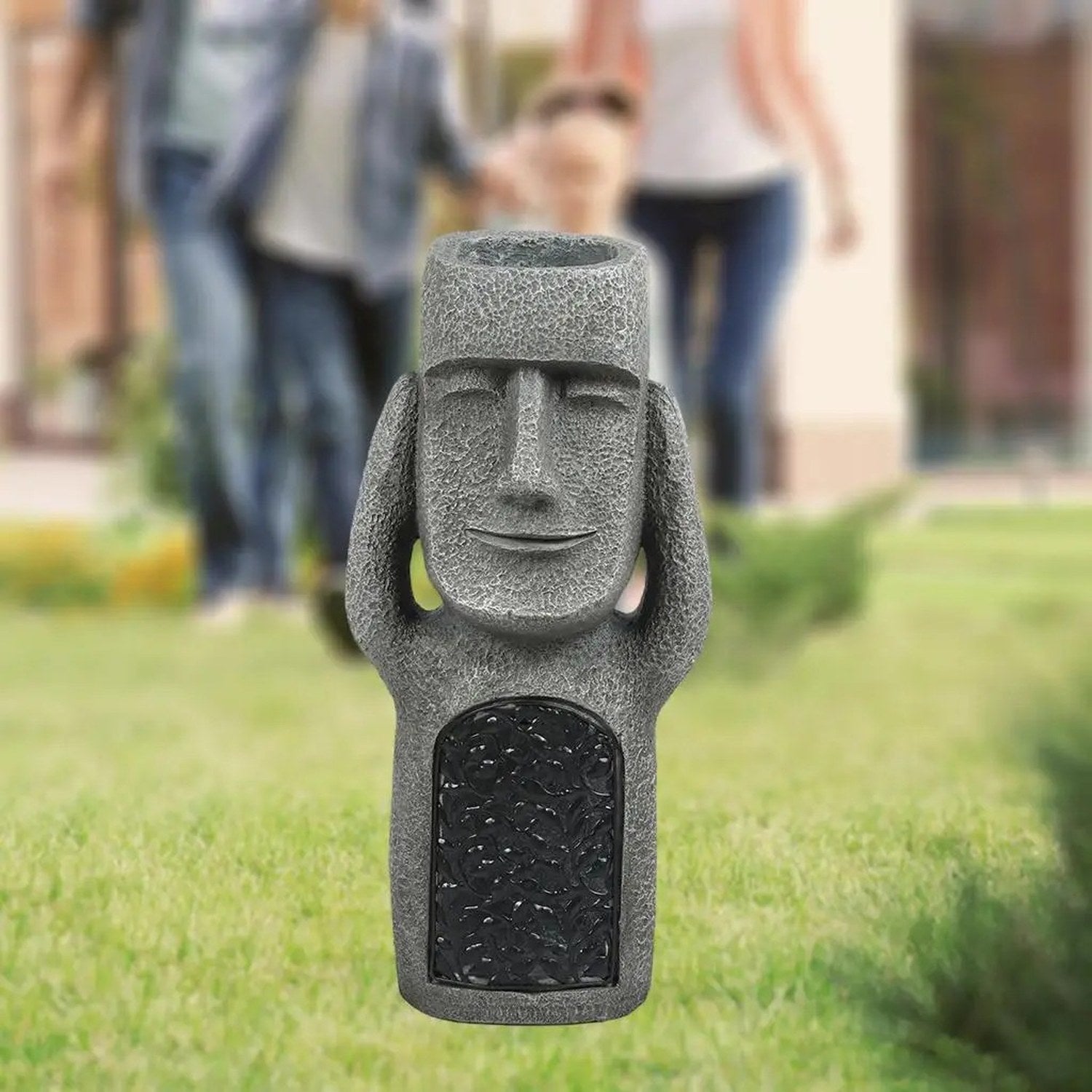 Statue Moai ornement de jardin sur pelouse verte avec famille en arrière-plan