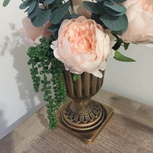 Vase romain urne bronze avec arrangement floral rose sur parquet