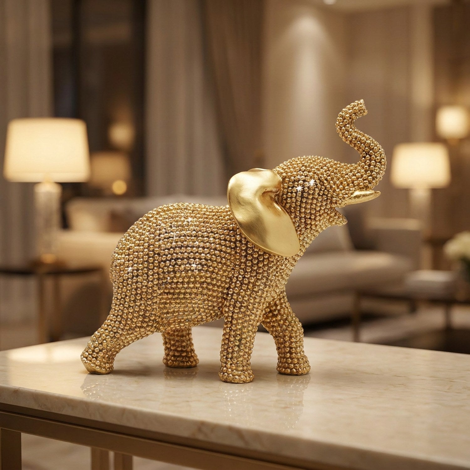 Statue éléphant doré à l'effet strass trompe levée posée sur une console marbre
