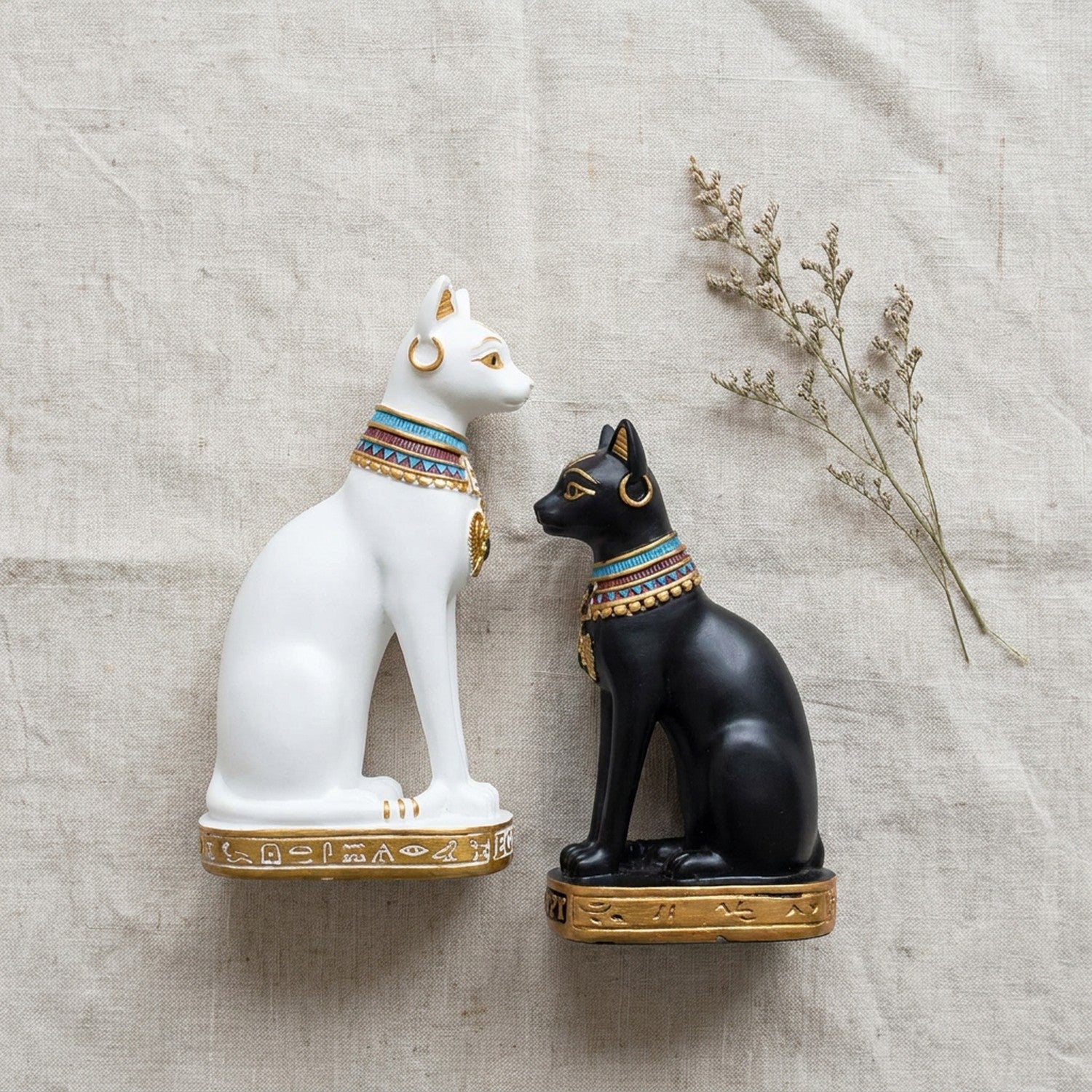 Duo statuettes chat Bastet blanche et noire côte à côte sur lin naturel