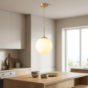 Suspension boule de verre opale dorée allumée au-dessus d'un îlot de cuisine moderne