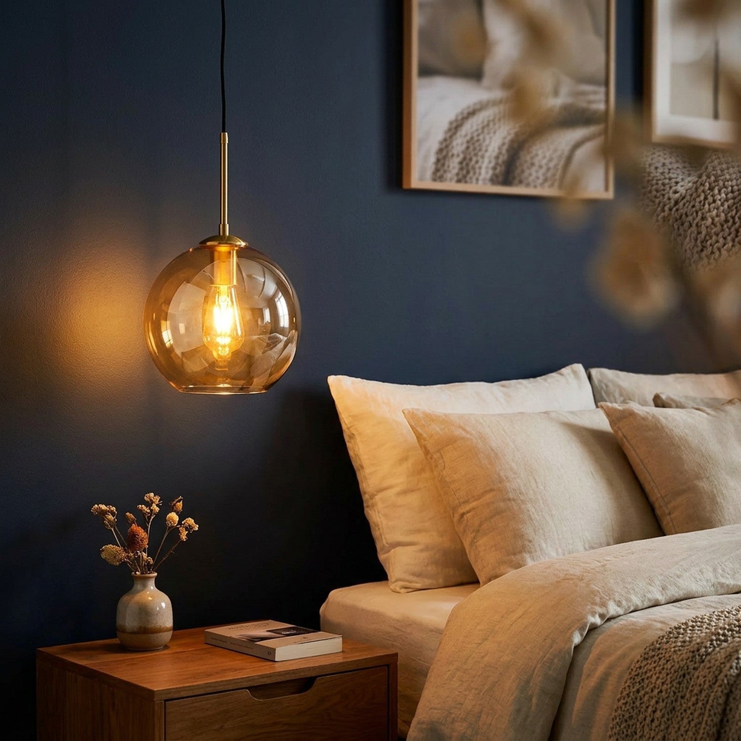 Suspension boule de verre ambrée avec armature dorée dans une chambre aux murs bleu nuit