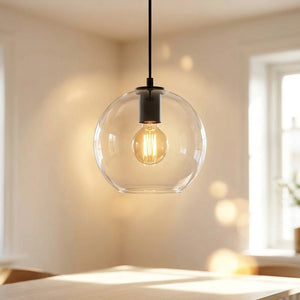 Suspension boule de verre transparente avec ampoule Edison filament allumée et armature noire dans un intérieur moderne