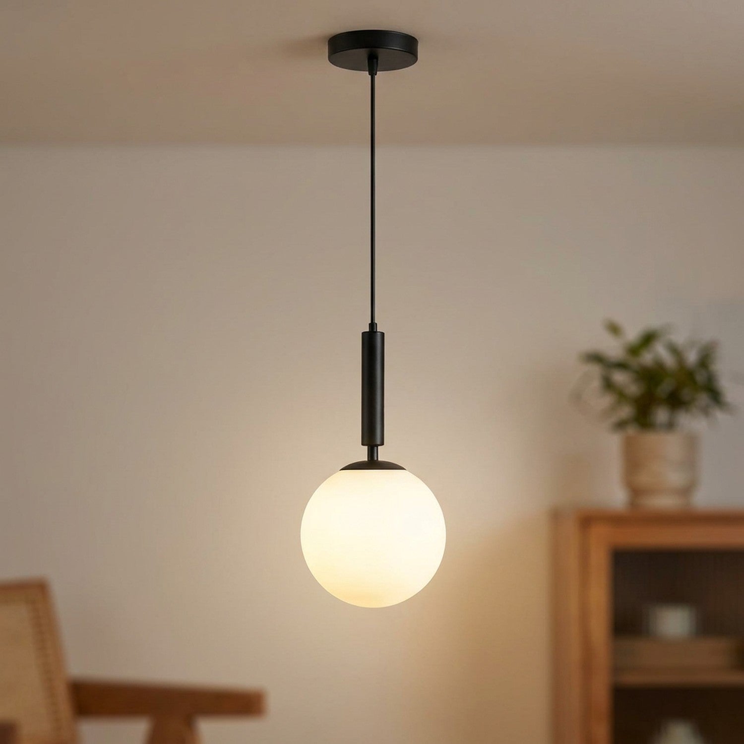 Suspension boule de verre dépoli blanc avec cordon noir allumée dans un intérieur chaleureux