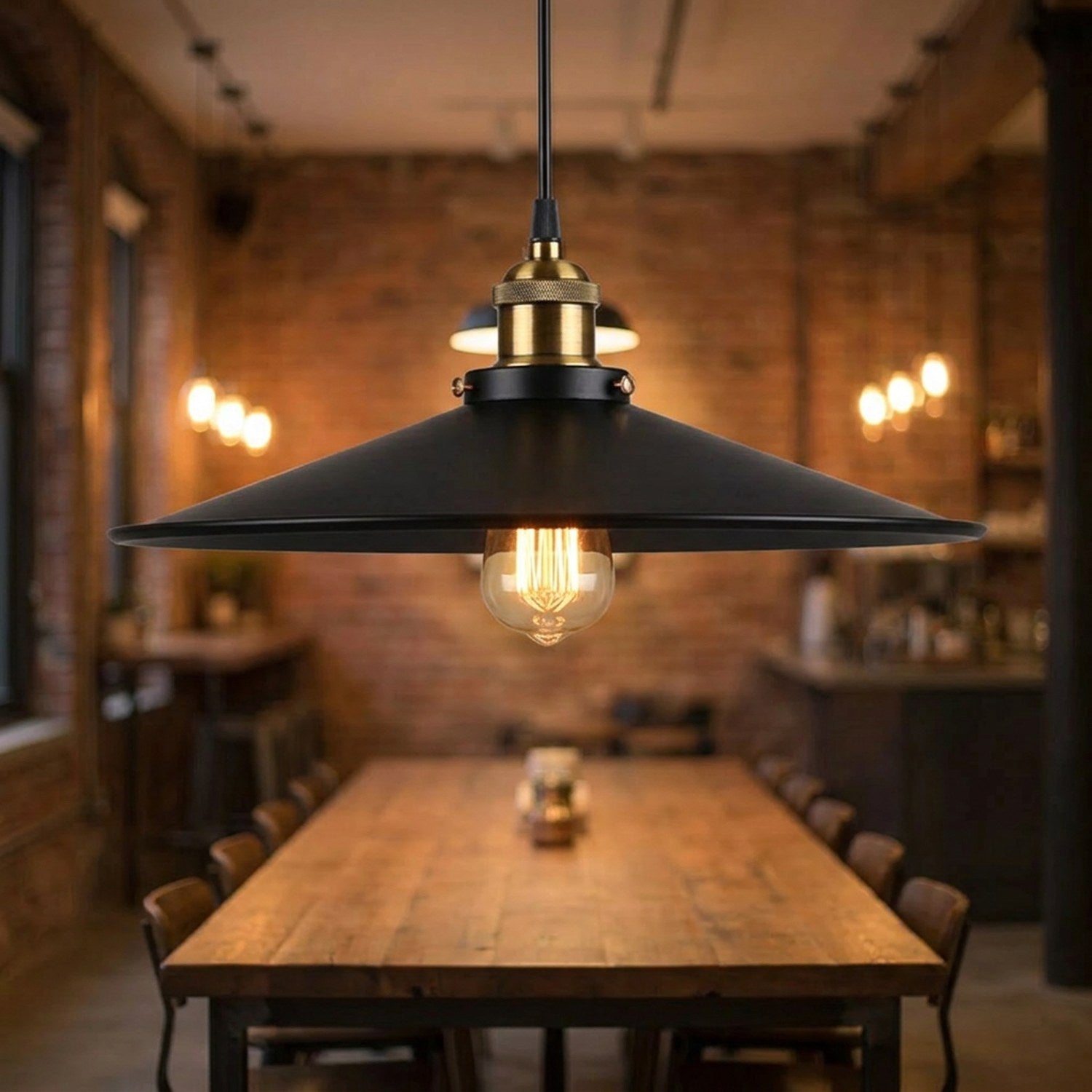 Suspension industrielle noire allumée au-dessus d'une grande table dans un loft