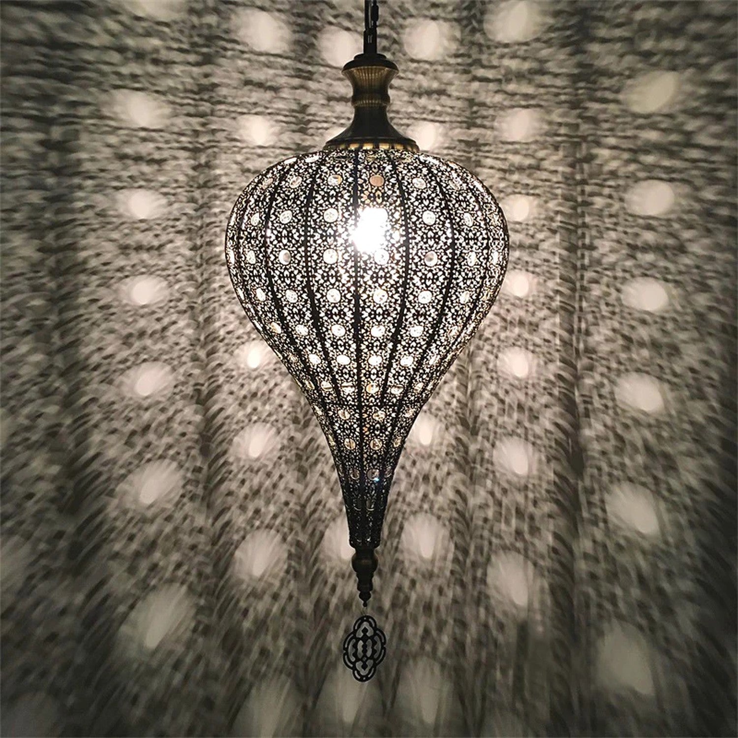 Suspension marocaine diffusant une lumière tamisée à motifs sur un mur