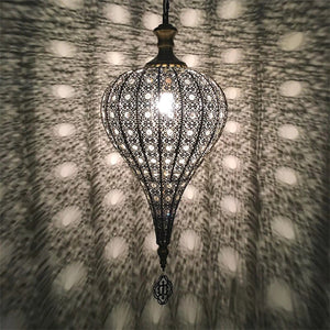 Suspension marocaine diffusant une lumière tamisée à motifs sur un mur