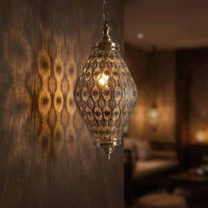 Suspension marocaine en métal doré ajouré allumée au-dessus d'une table dans une ambiance chaleureuse