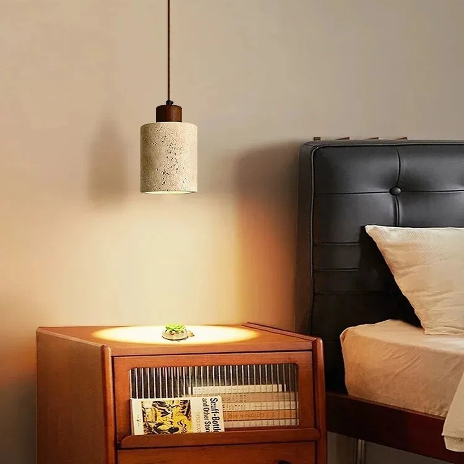 Suspension travertin Cylindre noyer allumée dans une chambre avec table de chevet livres