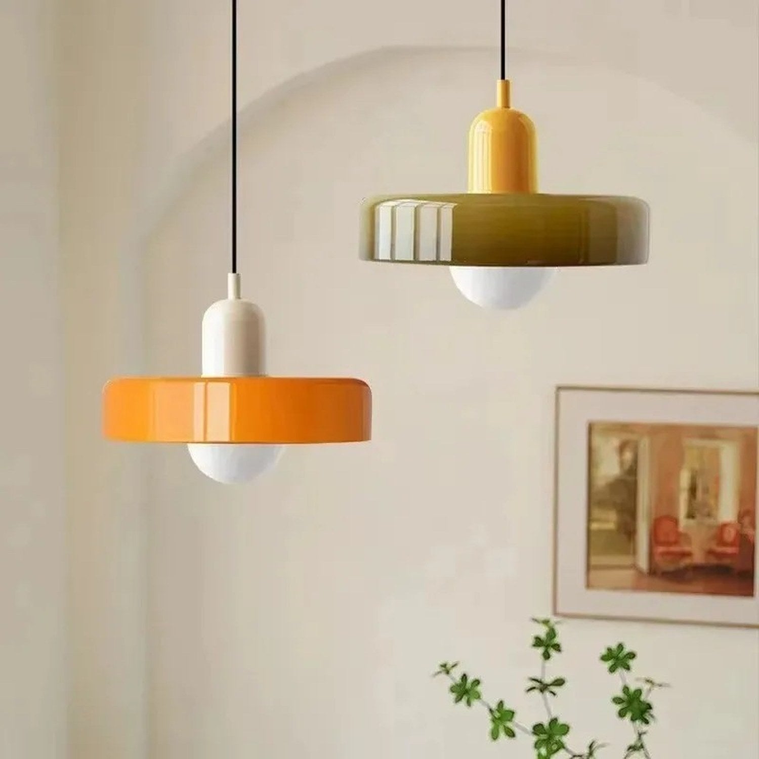 Deux suspensions en verre orange et vert olive suspendues au-dessus d'une table en bois