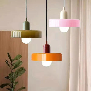 Trois suspensions en verre vert olive rose et orange dans un intérieur chaleureux