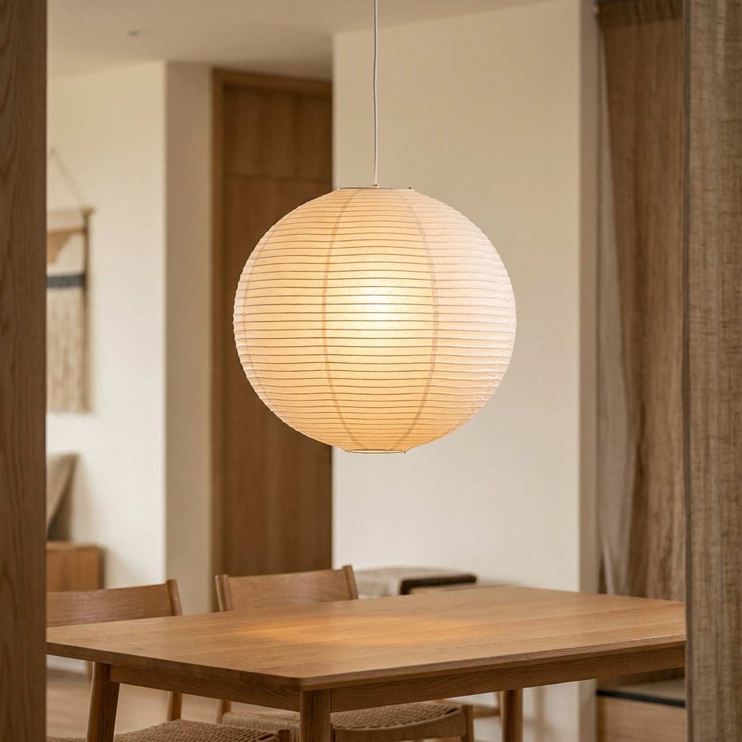 Suspension boule japonaise en papier de riz wabi-sabi, allumée dans une salle à manger Japandi