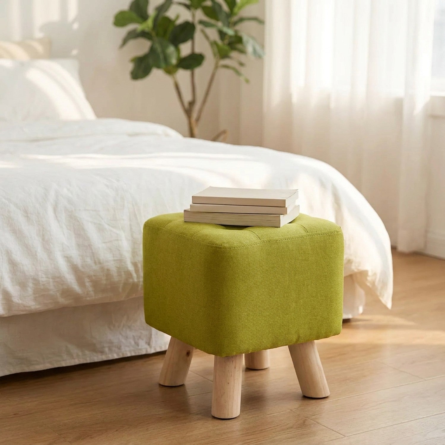 Tabouret en lin vert anis dans une chambre lumineuse avec des livres posés dessus