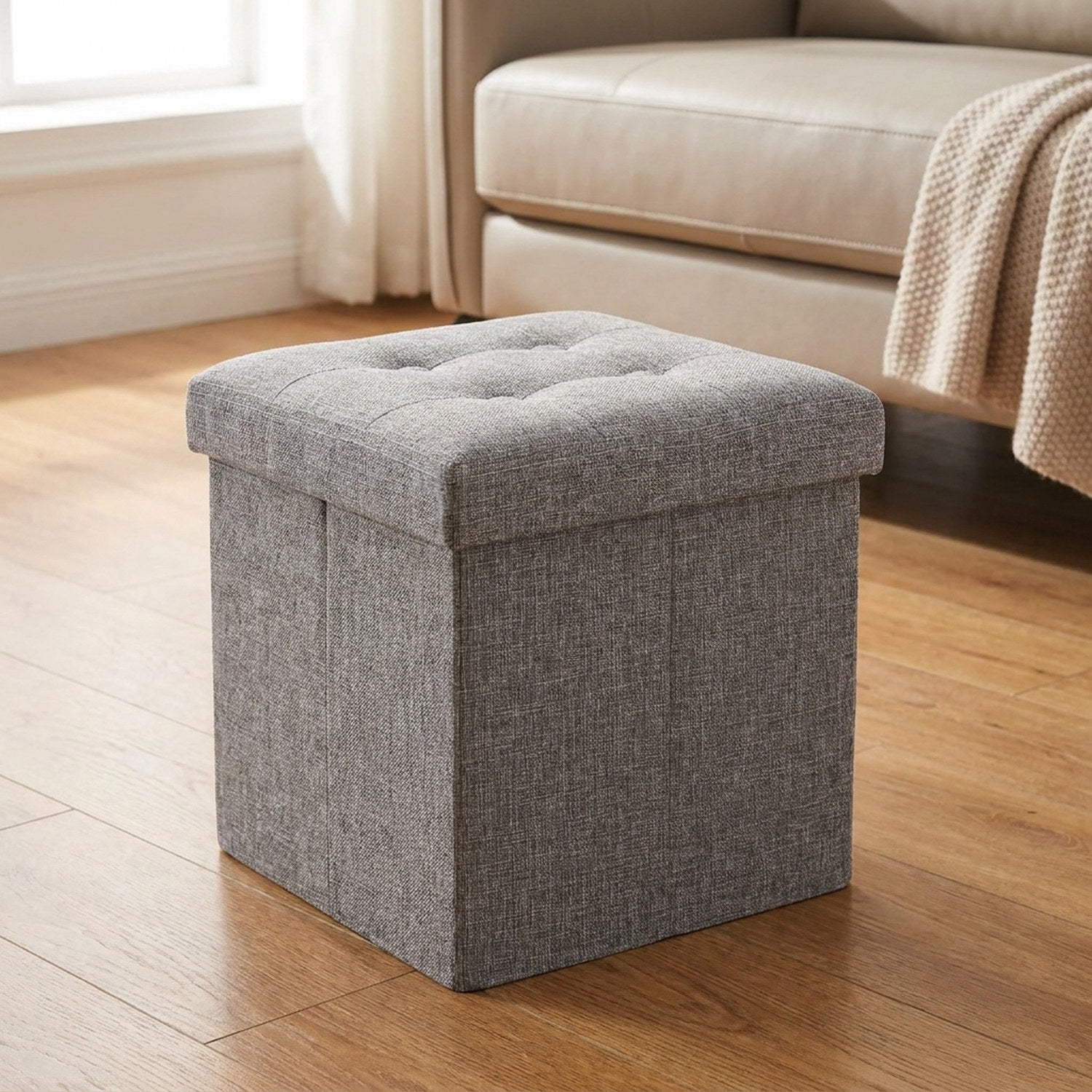 Tabouret pliant coffre de rangement gris avec assise rembourrée dans un salon