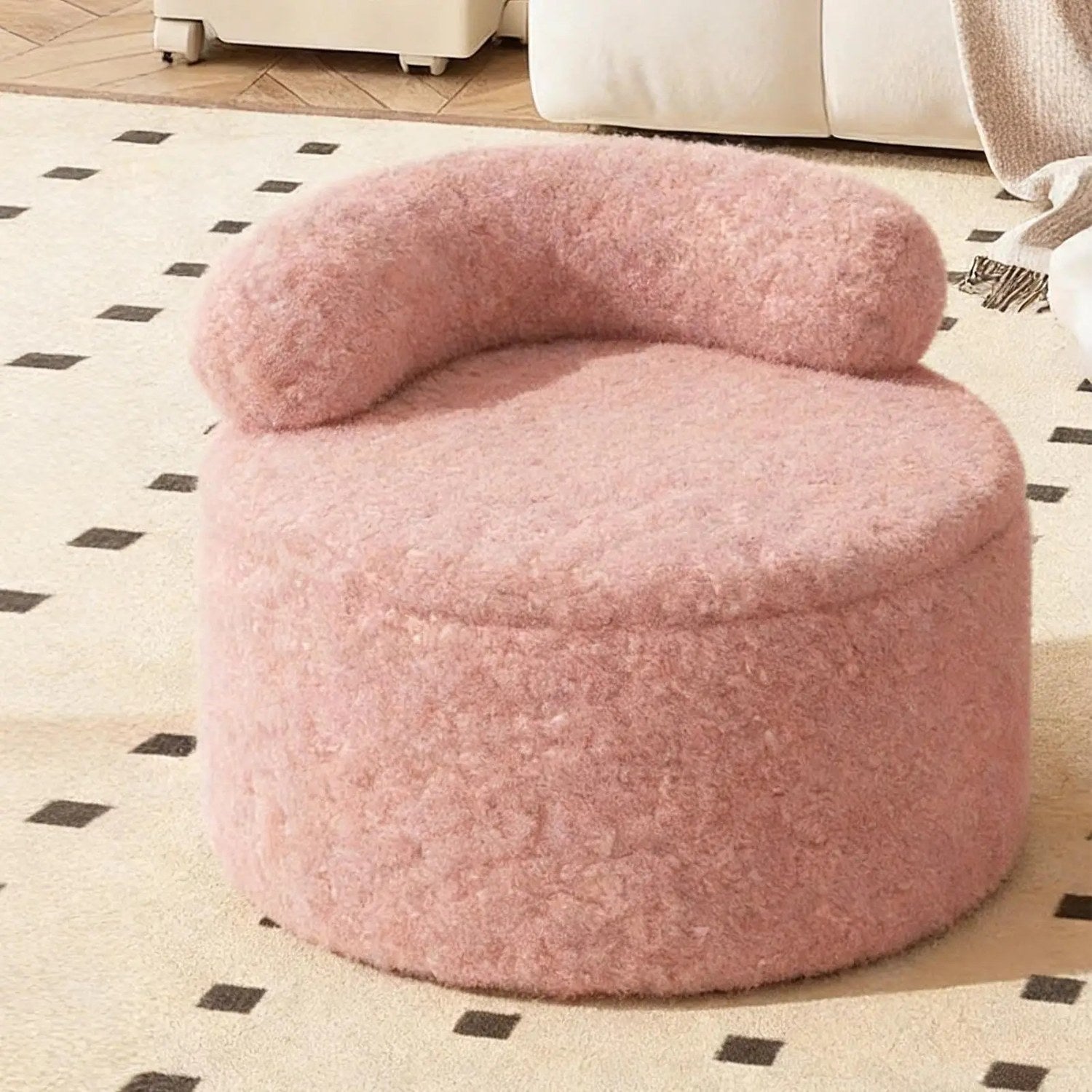 Tabouret pouf rond en bouclette rose posé sur un tapis de salon moderne