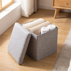 Tabouret de rangement ouvert révélant le coffre intérieur rempli de plaids et serviettes