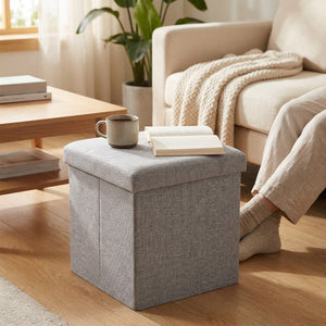 Tabouret pliable gris utilisé comme siège d appoint près d une table basse avec une tasse et un livre
