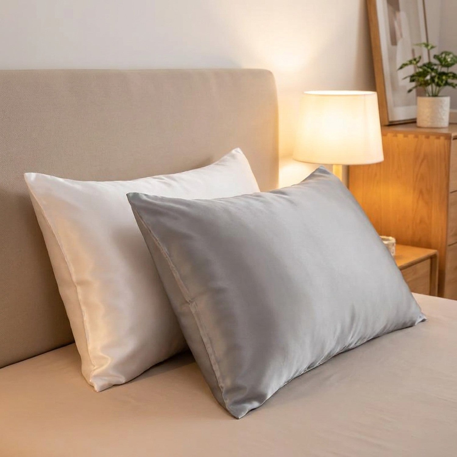 Taies d'oreiller en satin effet soie sur un lit dans une chambre moderne avec lampe de chevet