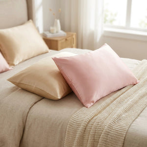 Taies d'oreiller en satin effet soie champagne et rose sur un lit cocooning