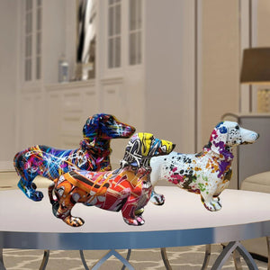 Trois statues teckel en résine avec motifs graffiti colorés posées sur une table basse de salon