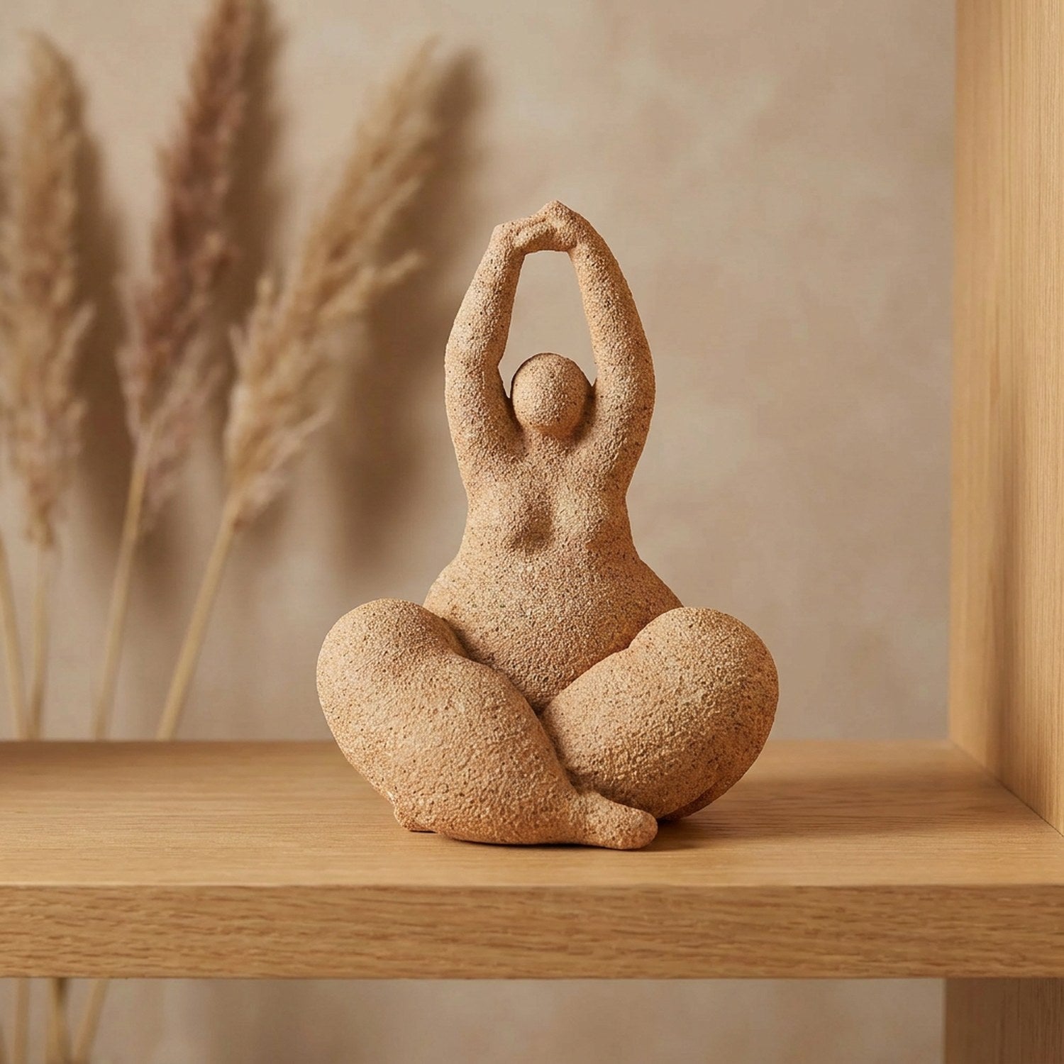 Statue de femme ronde en résine effet grès terracotta assise en méditation sur une étagère en bois