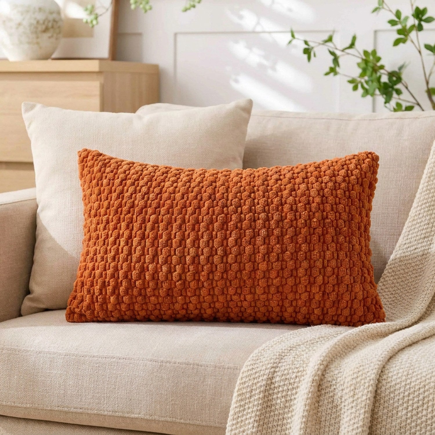 housse de coussin rectangulaire en maille texturée terracotta sur un canapé en lin