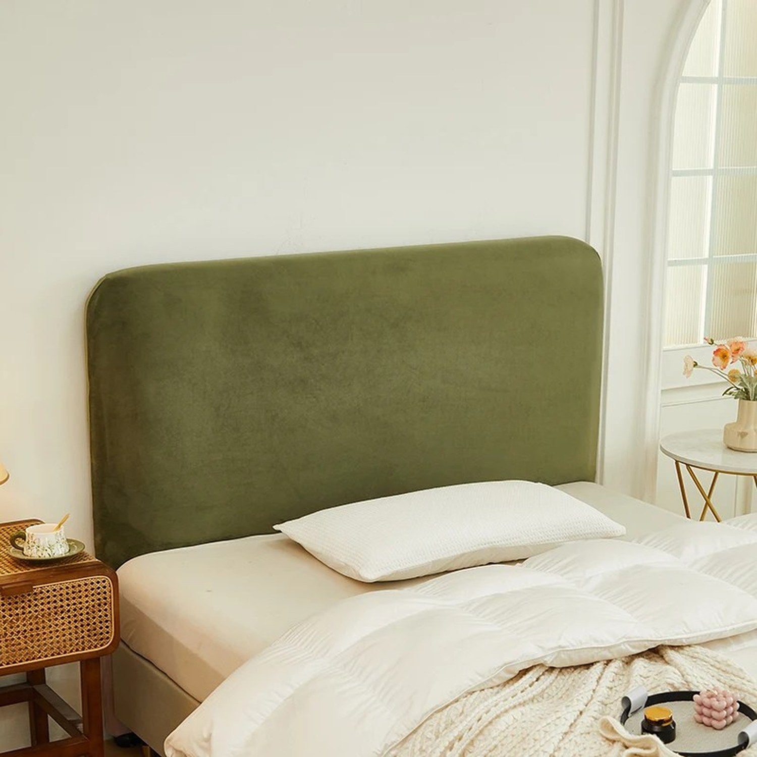 Housse de tête de lit verte en velours avec oreiller blanc et couette sur un lit