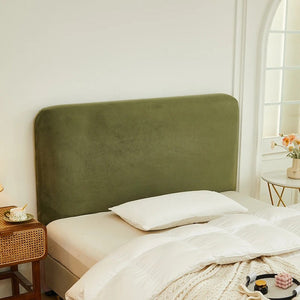 Housse de tête de lit verte en velours avec oreiller blanc et couette sur un lit