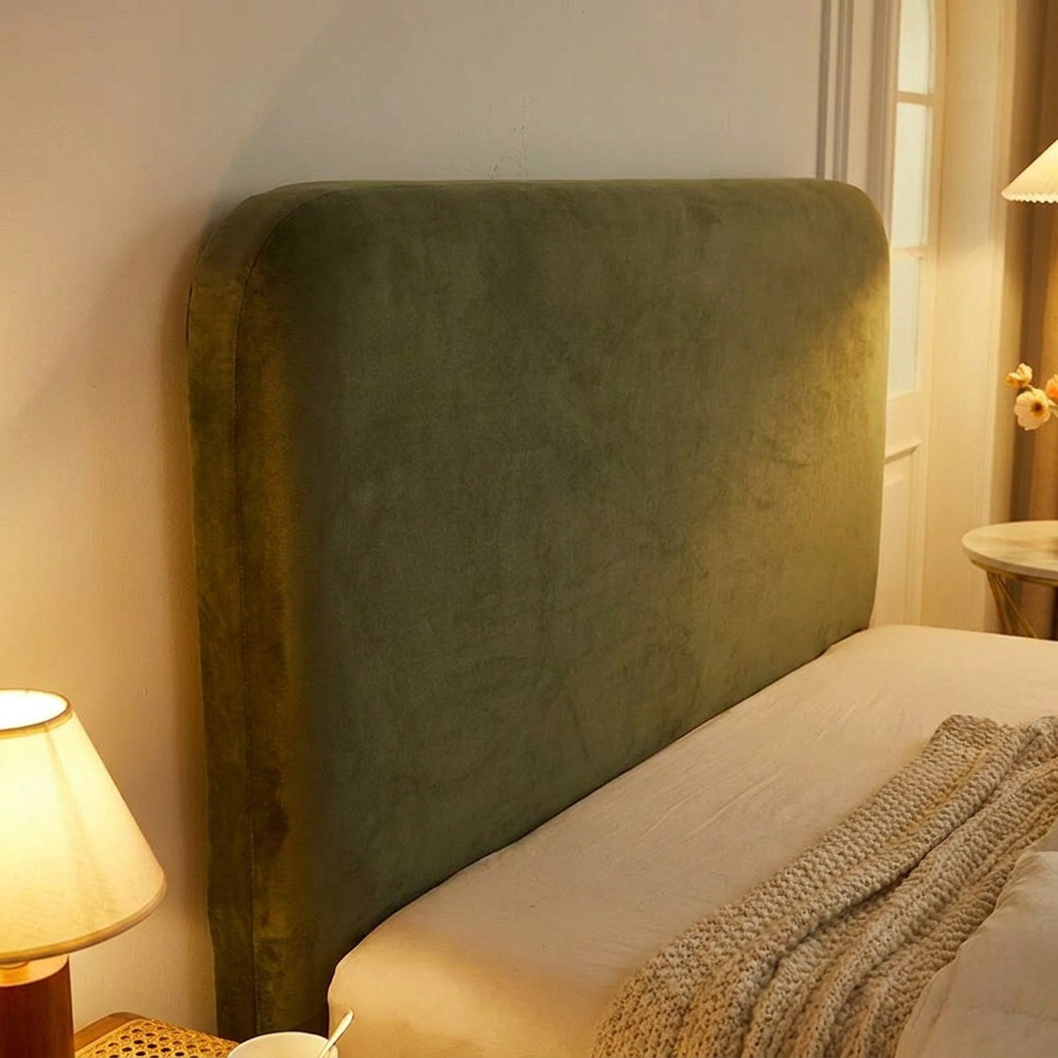Détail de la housse de tête de lit verte en velours avec lampe de chevet le soir
