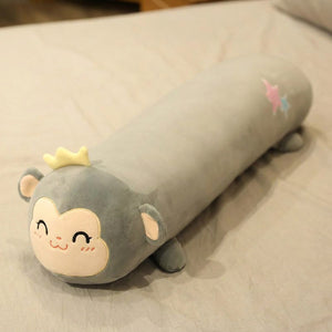 Traversin peluche en forme de singe kawaii posé sur un lit clair
