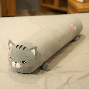 Traversin peluche en forme de chat tigré kawaii posé sur un lit clair