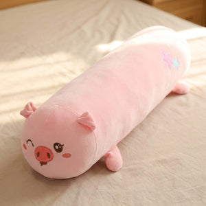 Traversin peluche en forme de cochon kawaii posé sur un lit clair