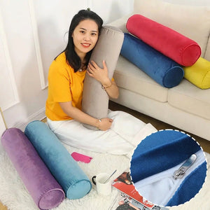 Traversin cylindrique en velours tenu dans les bras avec plusieurs coloris en arrière plan