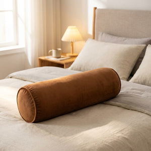 Traversin velours marron posé sur un lit dans une chambre chaleureuse