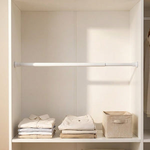 Tringle extensible blanche installée dans un placard pour ranger et suspendre du linge