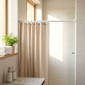 Tringle extensible blanche tenant un rideau de douche en lin dans une salle de bain lumineuse