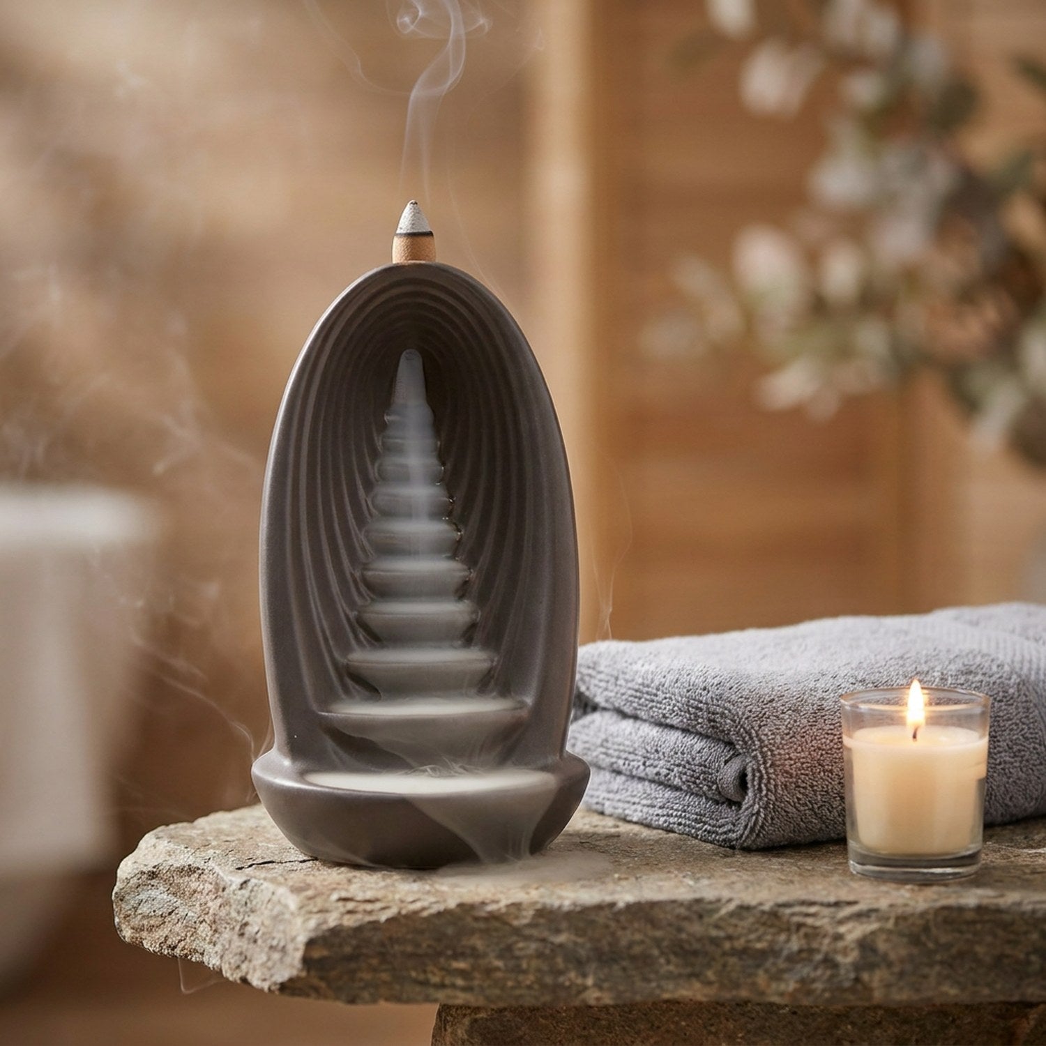 Brûleur d'encens à reflux sur une étagère spa en pierre avec serviette pliée et bougie allumée